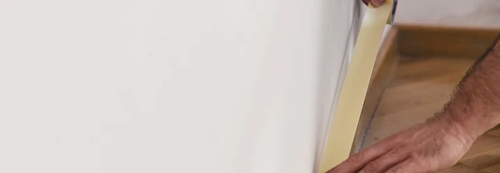 Person klebt Malerkrepp an eine Wand